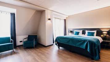 Een moderne hotelkamer met een groot bed, een zithoek met een stoel en uitzicht op het omliggende landschap.