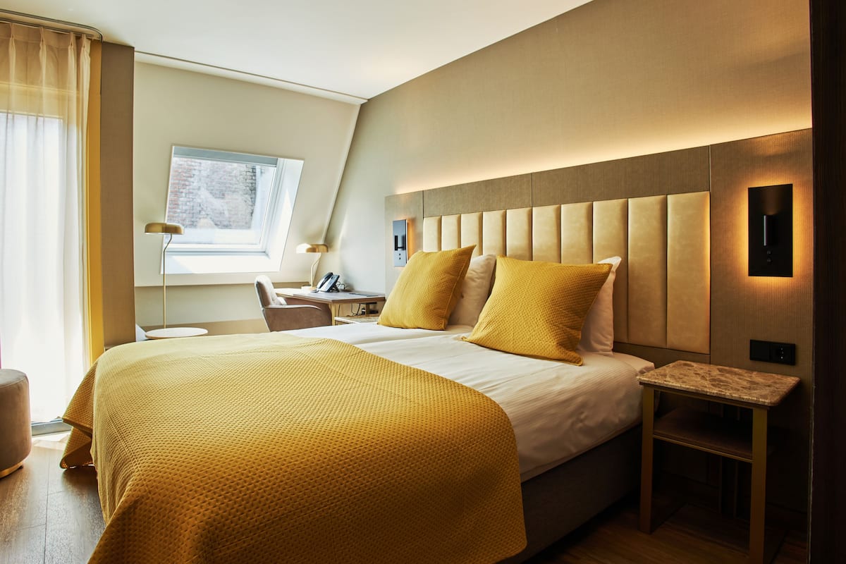 A modern hotel room with a large bed, a desk, and a chair.