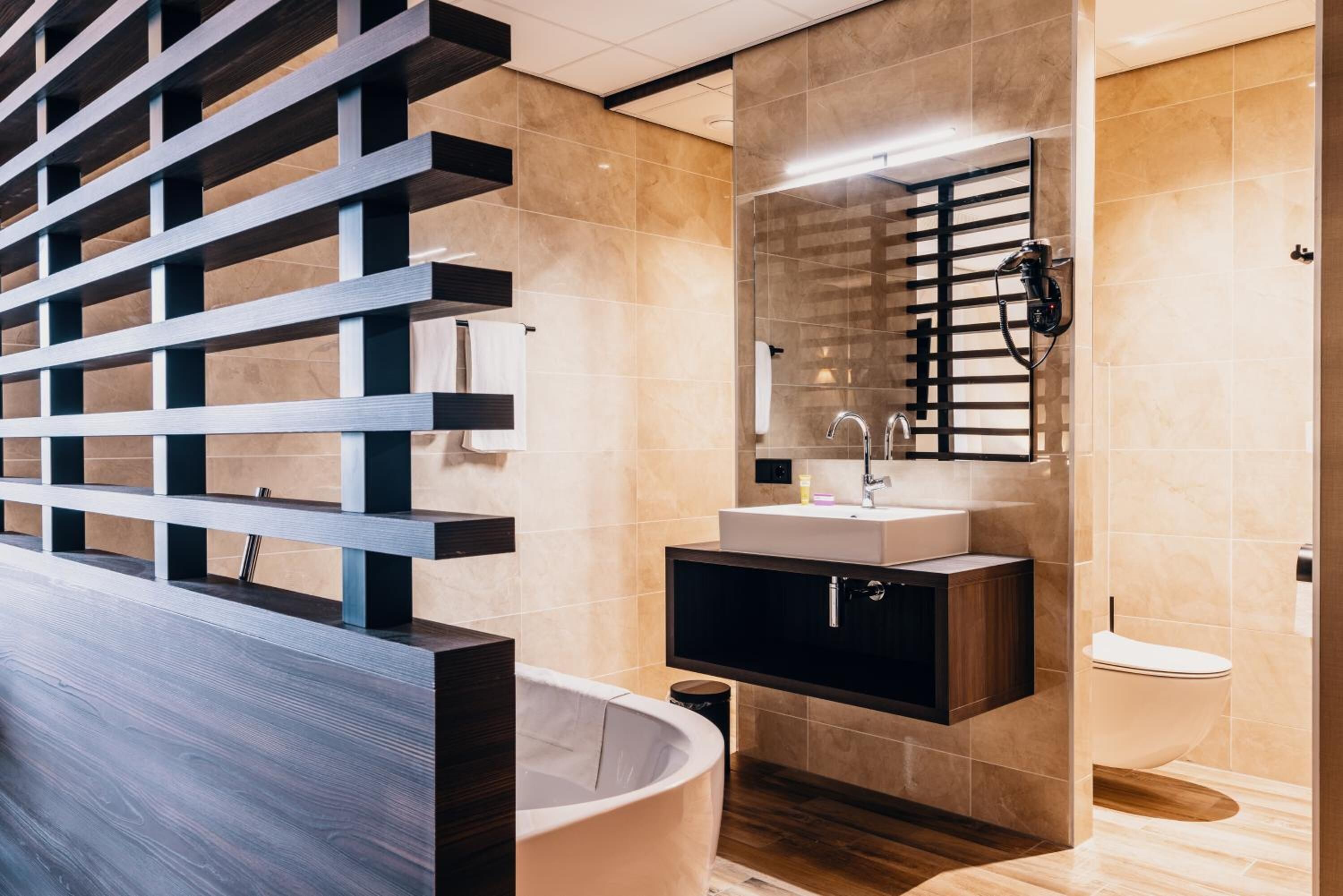 Ein modernes Badezimmer mit einer freistehenden Badewanne, einem Waschtisch mit Spiegel und einer Toilette.
