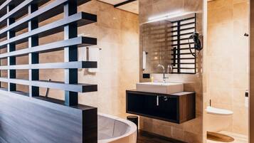 A modern bathroom with a freestanding bathtub, a vanity with a mirror, and a toilet.