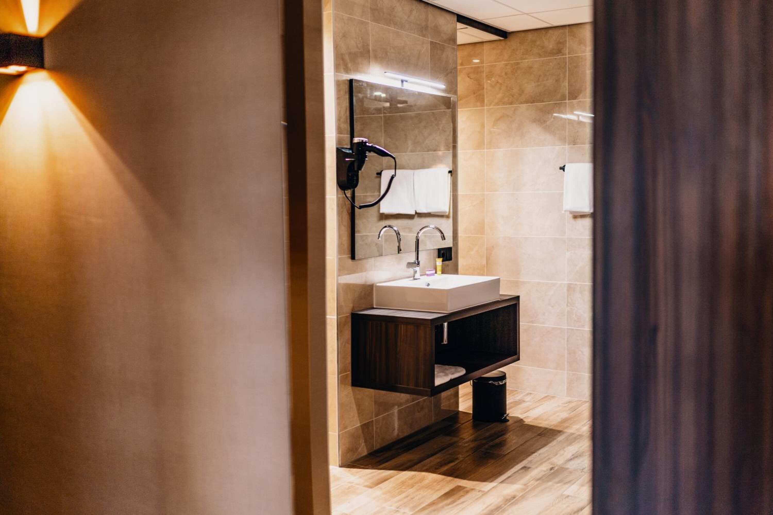 Un baño moderno con un espejo grande, un lavabo y un perchero para toallas.