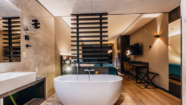 A modern bathroom with a freestanding bathtub, a vanity with a mirror, and a seating area with a table and chairs.