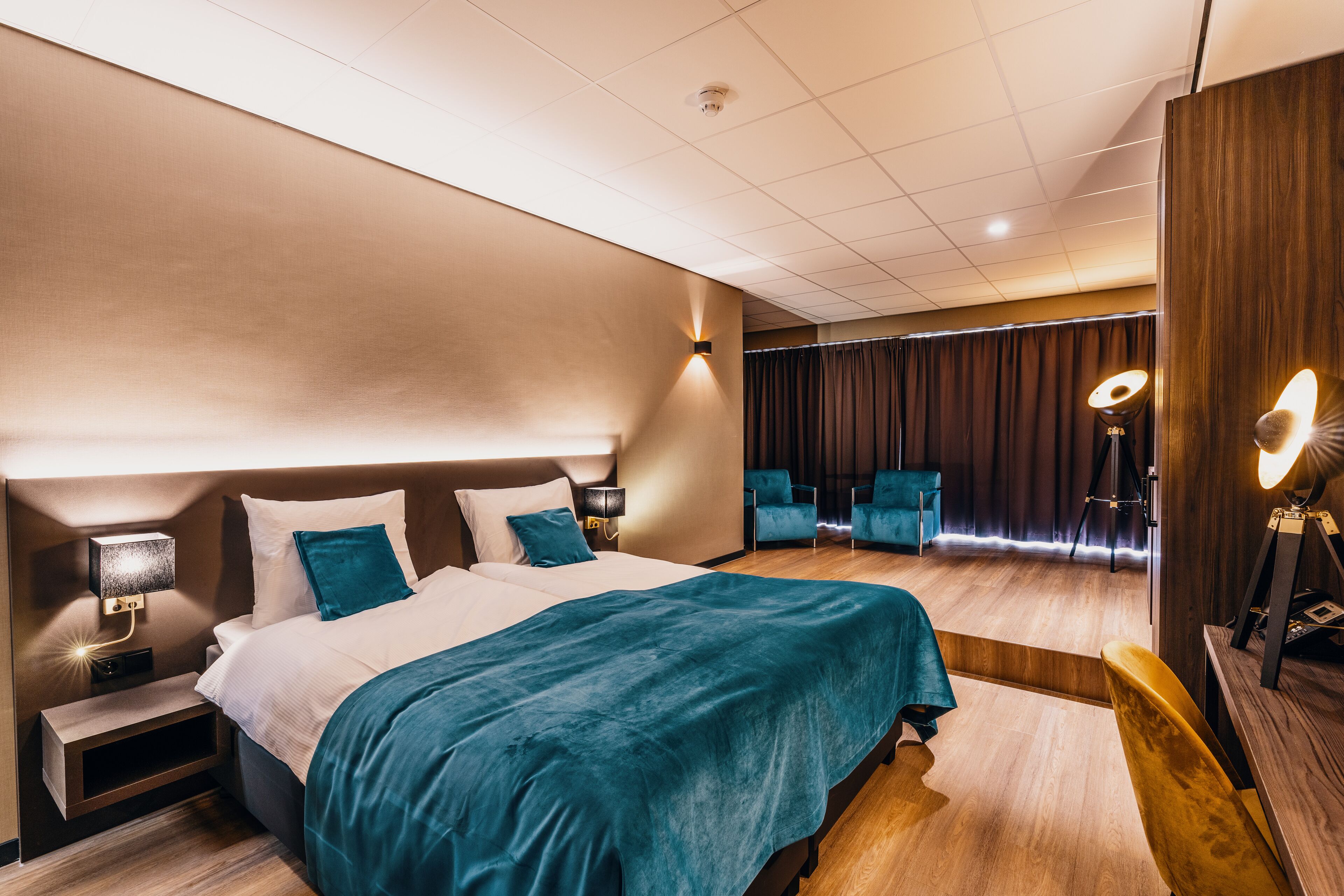 A modern hotel room with a large bed, bedside tables, a desk, and a chair.