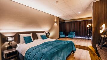 A modern hotel room with a large bed, bedside tables, a desk, and a chair.