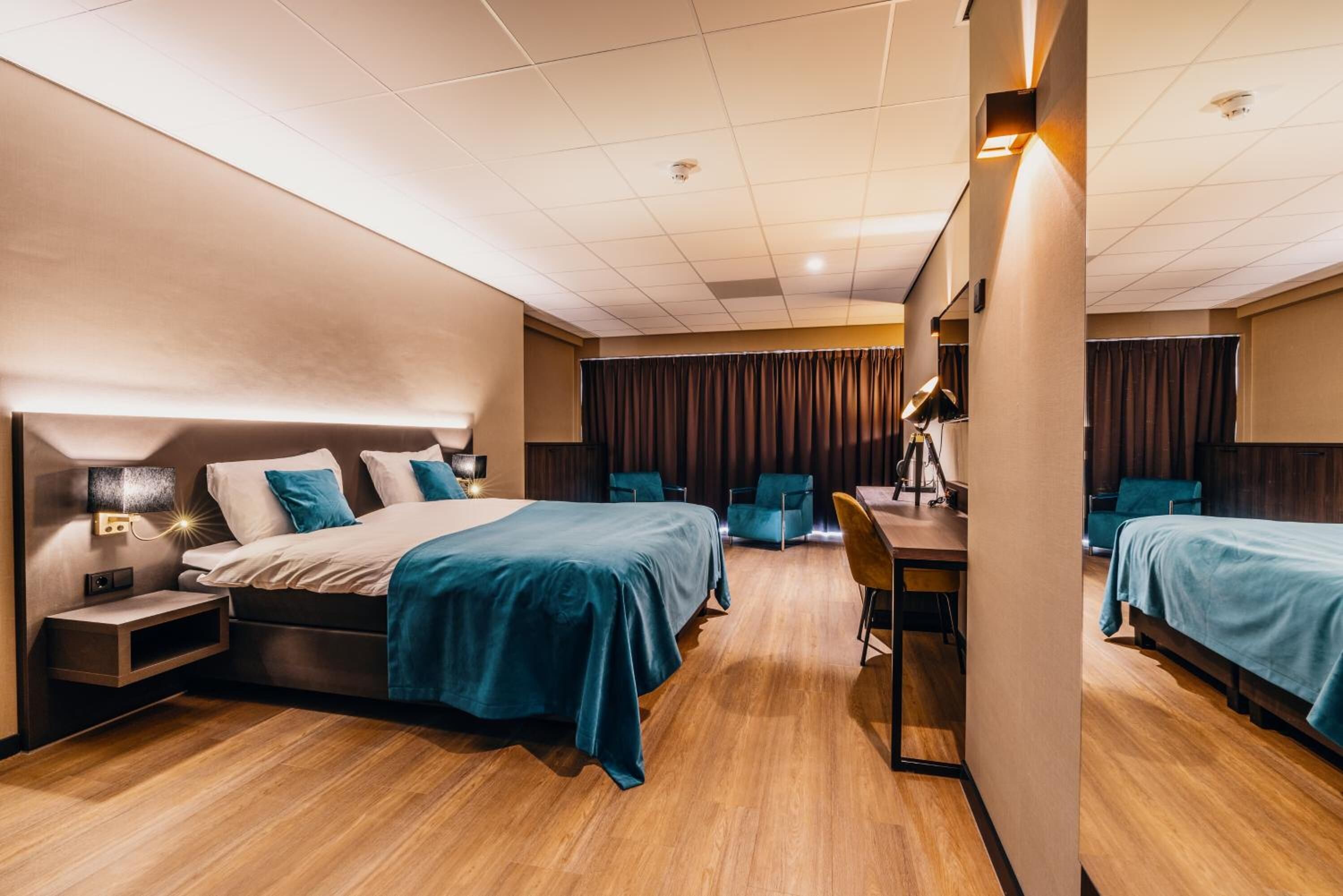 A hotel room with a bed, desk, chair, and two armchairs.