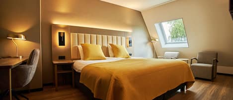 A modern hotel room with a large bed, a desk, and a chair.