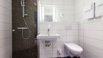 A modern bathroom with a glass-enclosed shower, a white sink, and a toilet.