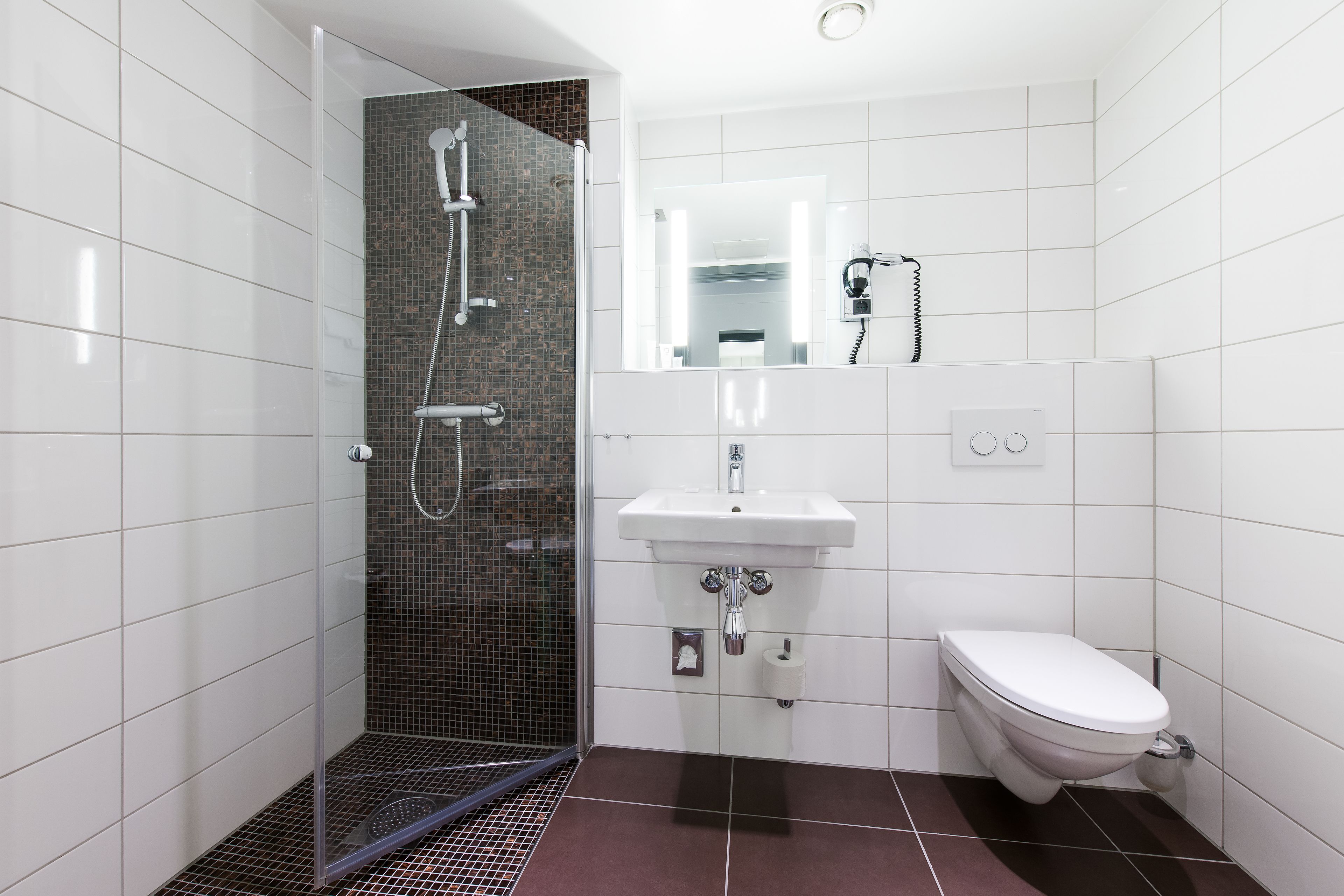 Un baño moderno con ducha de vidrio, lavamanos blanco y un inodoro.