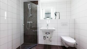 A modern bathroom with a glass-enclosed shower, a white sink, and a toilet.
