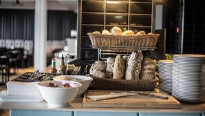A buffet setup with bread baskets, plates, and bowls on a counter.