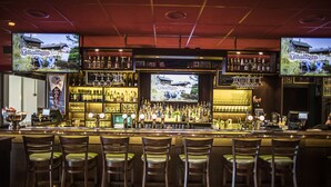 A bar with multiple TVs, a variety of bottles, and several bar stools. - Thon Hotel Victoria Hamar (Hamar)