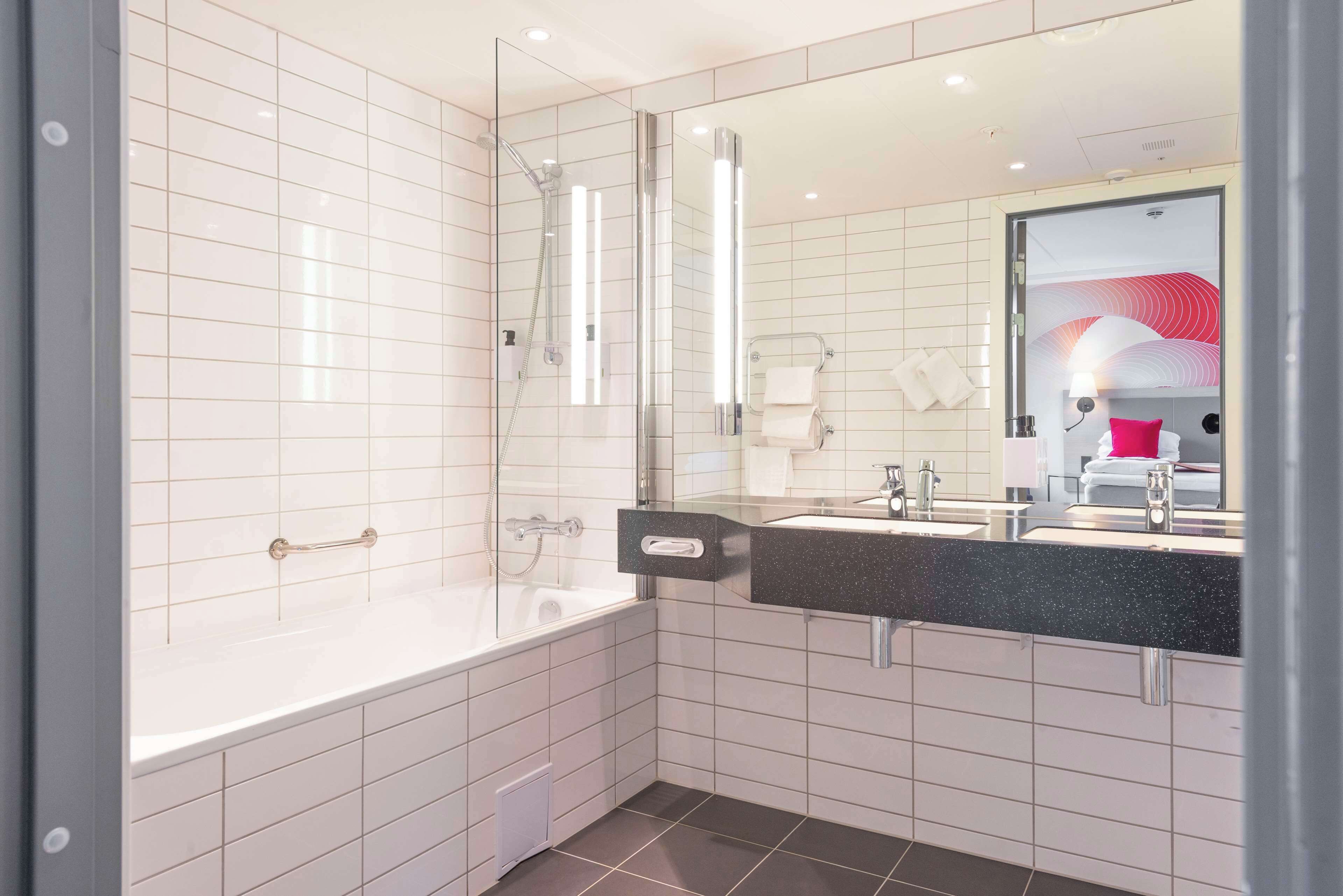 A modern bathroom with a glass-enclosed shower, a white bathtub, and a black countertop sink.