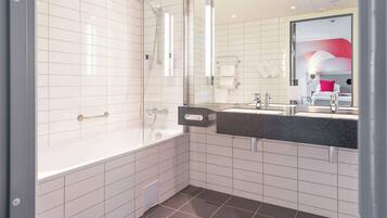 A modern bathroom with a glass-enclosed shower, a white bathtub, and a black countertop sink.