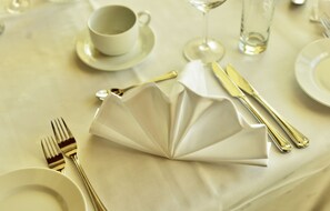 A table set for a meal with a folded napkin, a wine glass, and cutlery.