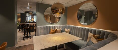 A modern interior with a seating area featuring a marble table and cushioned benches.