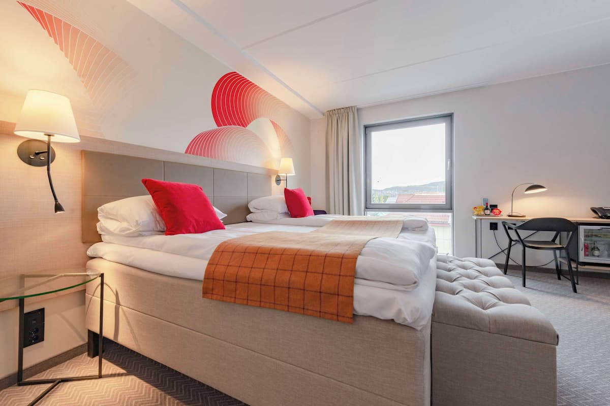 A hotel room with two beds, a desk, and a chair.