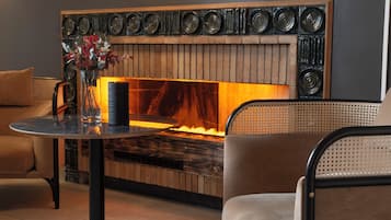 Een moderne zithoek met een open haard, een ronde tafel en comfortabele zitplaatsen.