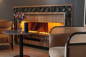 A modern lounge area with a fireplace, a round table, and comfortable seating. - Scandic Meyergården (Mo-I-Rana)