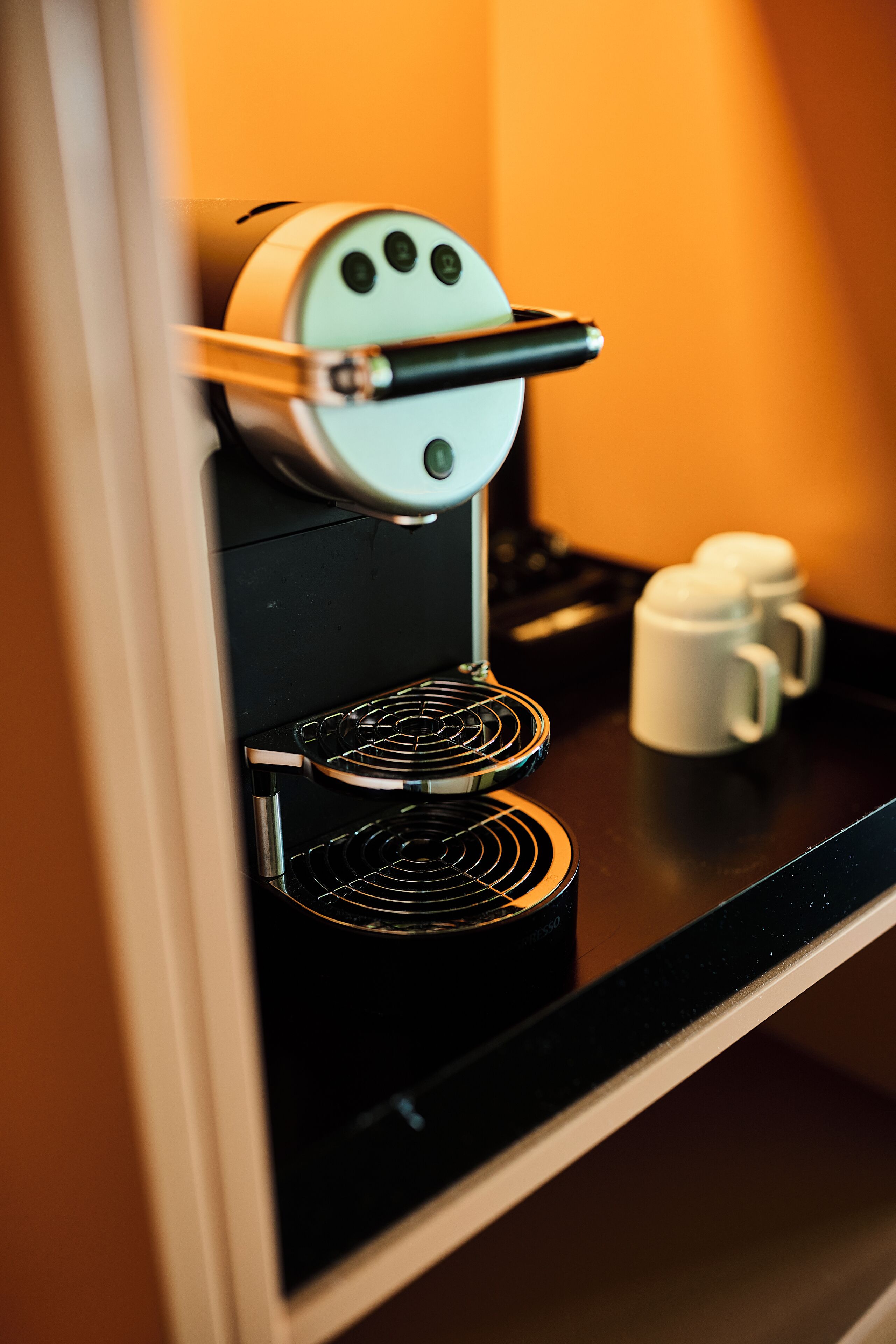 Una cafetera con un portalatas y una taza sobre una encimera.