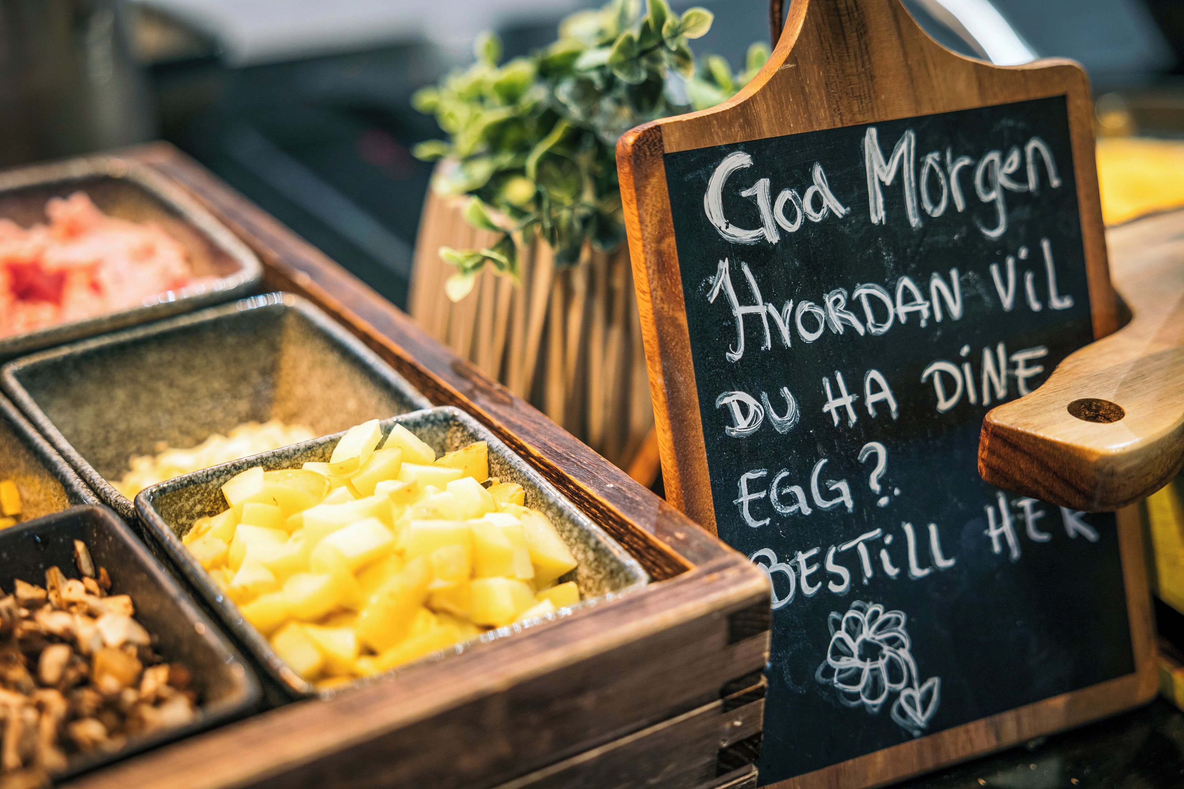 A breakfast buffet with various food options and a sign with handwritten text.