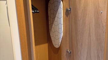 Une armoire en bois avec un fer à repasser suspendu et un objet décoratif sur l’étagère inférieure.