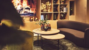 A cozy living room with a fireplace, a sofa, a coffee table, and a bookshelf.
