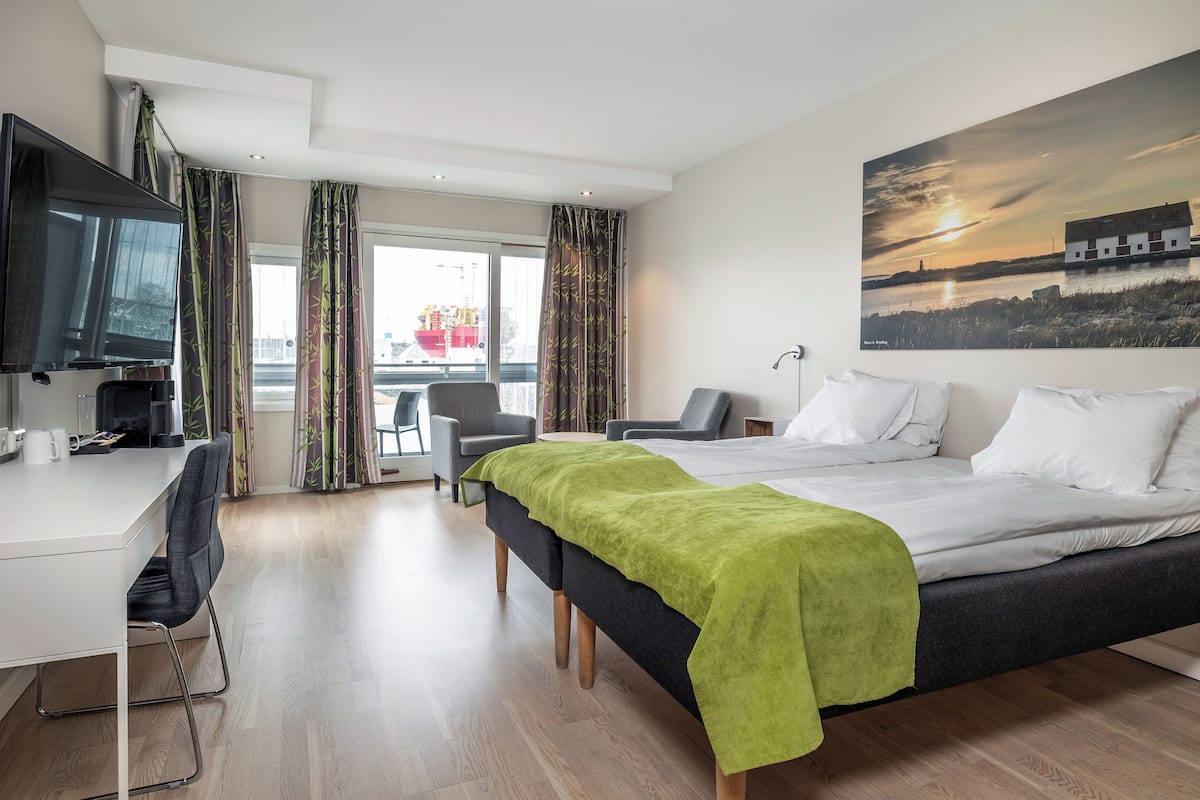 Moderni hotellihuone, jossa on sänky, työpöytä ja televisio.