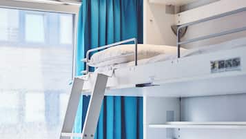 A bunk bed with a ladder, a window with blue curtains, and a white wall.