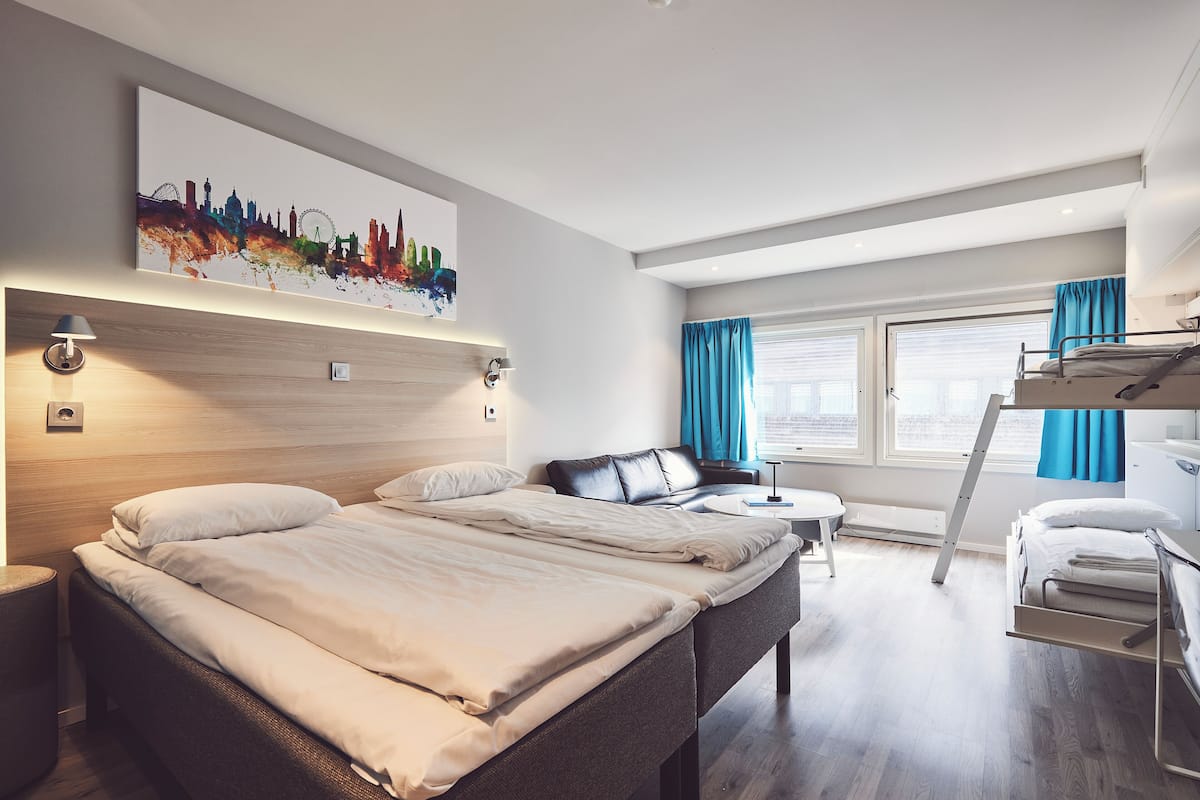 Moderni hotellihuone, jossa on suuri sänky, työpöytä, tuoli ja kerrossänky.