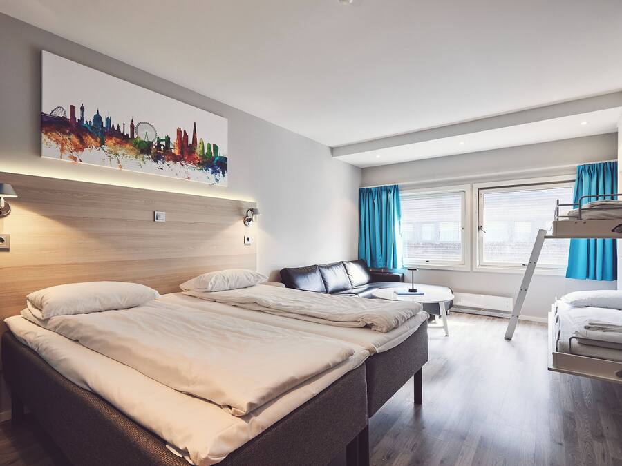 Una habitación de hotel moderna con una cama grande, un escritorio, una silla y una cama individual.