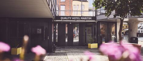 The entrance to Quality Hotel Maritim with a clear view of the street and neighboring buildings.