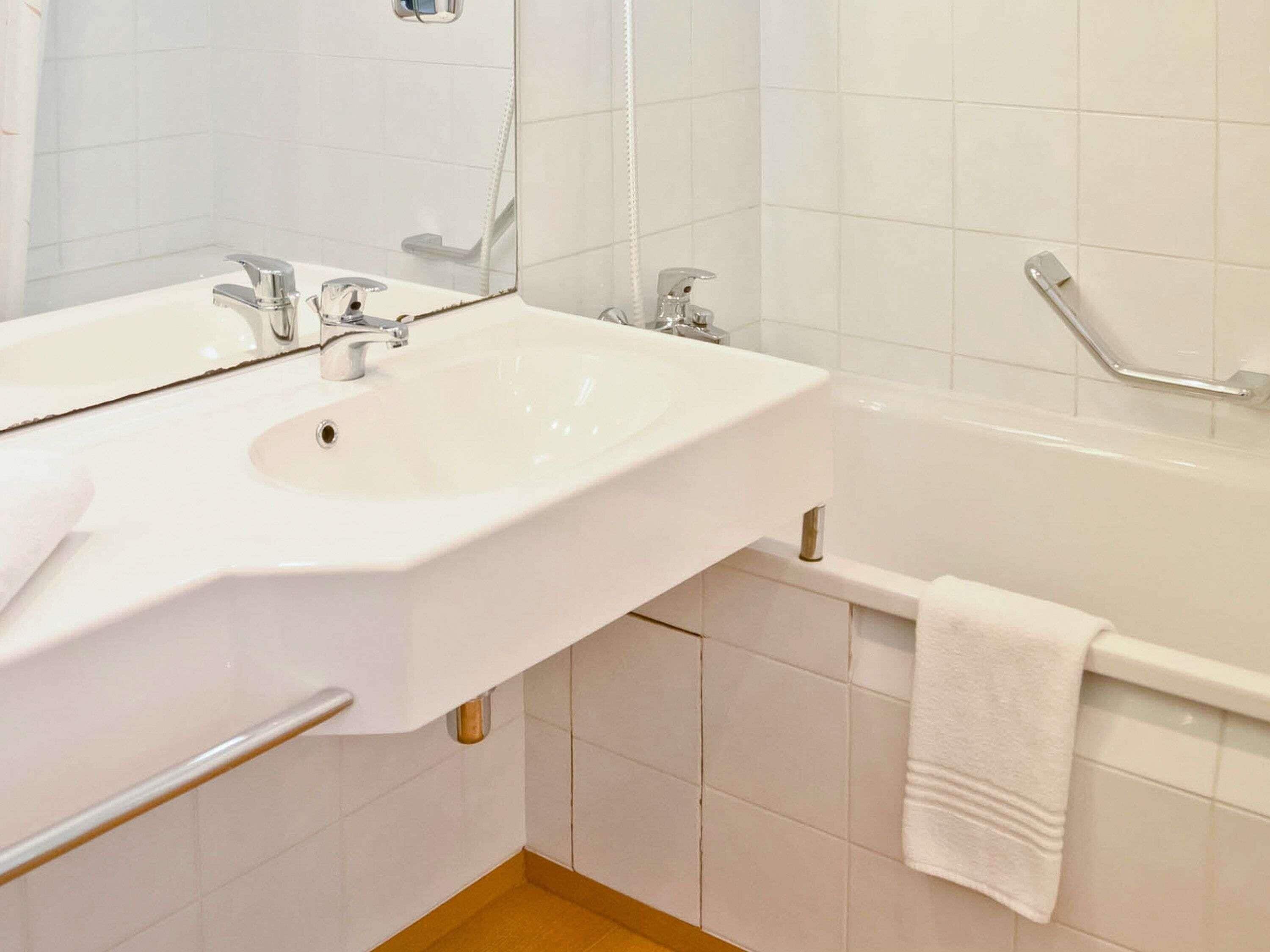 Ein Badezimmer mit Waschbecken, Spiegel und Badewanne.