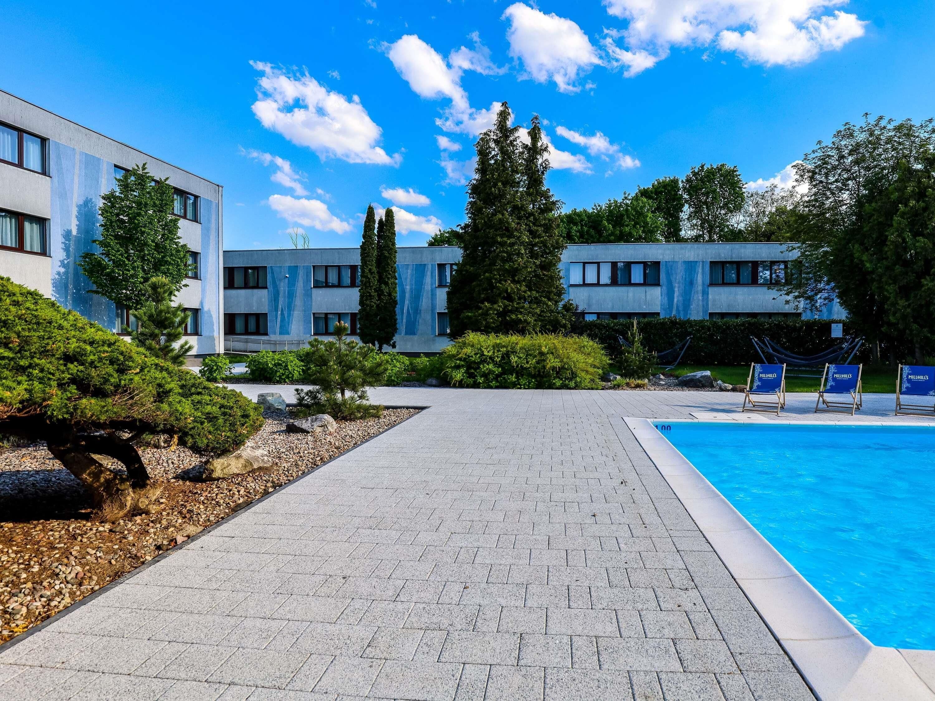 Edifici modern amb piscina, camins pavimentats i jardineria ben cuidada.