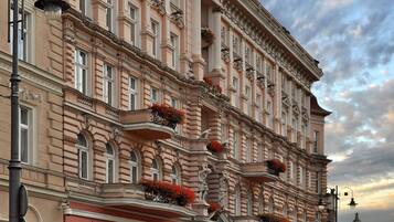 Un edificio histórico con arquitectura clásica, que presenta balcones ornamentales y una llamativa escultura de águila.