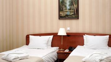 Une chambre d’hôtel avec deux lits, une table de chevet, une lampe et un tableau au mur.