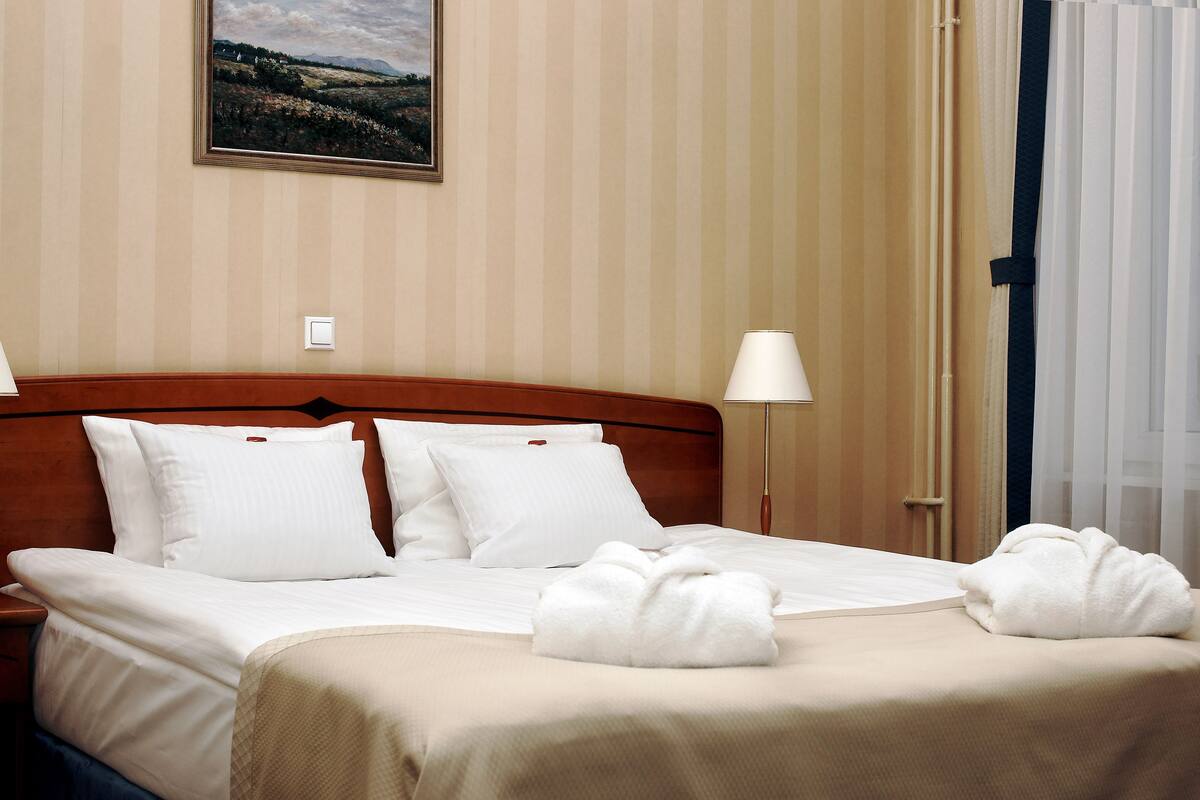 Ein Hotelzimmer mit Bett, Kissen, Decke und Handtüchern.