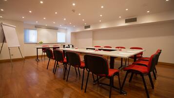 A conference room with a long table, red chairs, a whiteboard, and a projector.