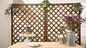 A wooden table with a white plate, a metal watering can, and a vase with flowers. - Legendary Porto Hotel (Porto)