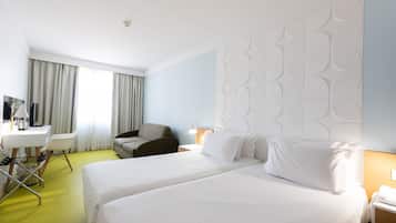 A hotel room with a large bed, a desk, a chair, and a television.