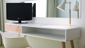 A modern room with a white desk, a television, a pair of white lamps, and a white chair. - Legendary Porto Hotel (Porto)
