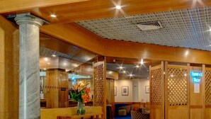 Un hall d’entrée avec un comptoir de réception, un espace bar et un coin salon avec des fauteuils à motifs.