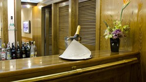 Un coin bar avec une bouteille de champagne, un vase de fleurs et diverses bouteilles de spiritueux.