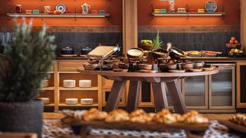 A kitchen with wooden cabinets, a round table with various bowls and dishes, and a potted plant in the foreground.