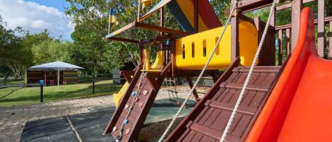 A playground with a slide, climbing area, and a covered seating area.