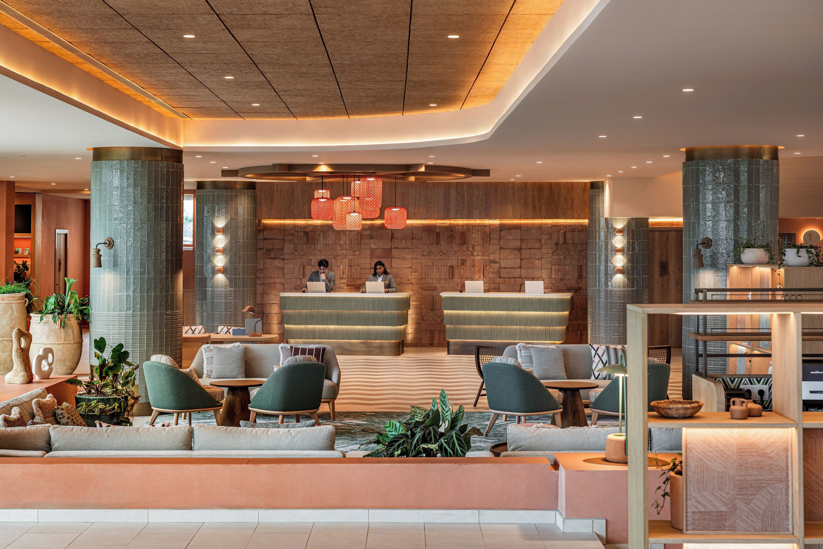 Um lobby moderno com balcão de recepção, área de estar e plantas decorativas.