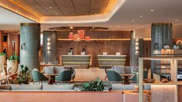 Um lobby moderno com balcão de recepção, área de estar e plantas decorativas.