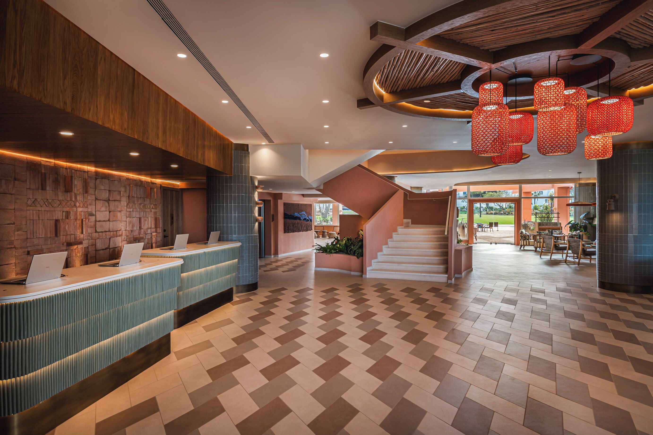 A reception area with a check-in counter, a staircase, and a view of the outdoor area.