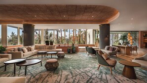 A spacious lobby with a large seating area, a central coffee table, and a view of palm trees and buildings. - Hyatt Regency Vilamoura Algarve (Loule)