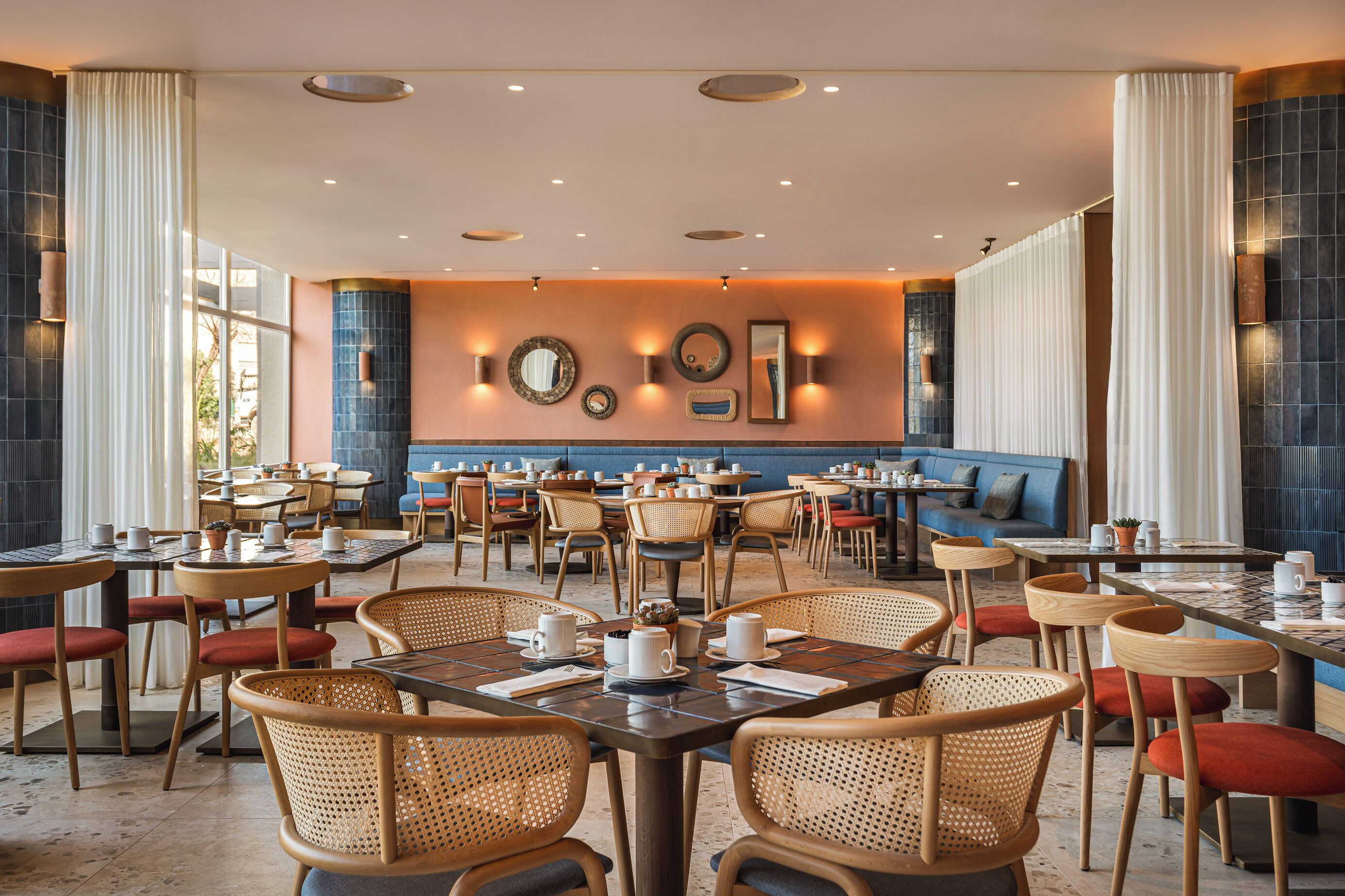 A spacious dining area with multiple tables and chairs, a blue cushioned seating area, and wall-mounted decorative items.