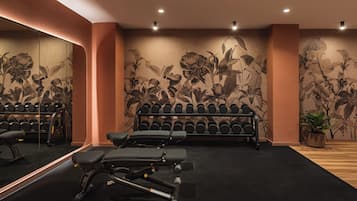 Un gimnasio con equipo de ejercicio, un espejo grande y un mural floral.